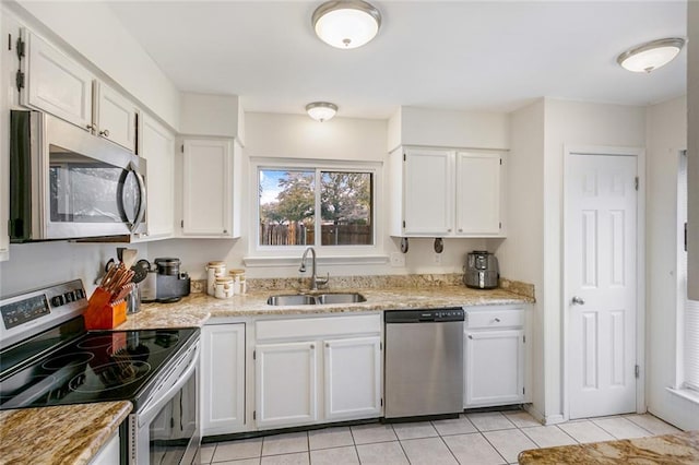 kitchen featuring white cabinets, light tile floors, stainless steel appliances, light stone countertops, and sink