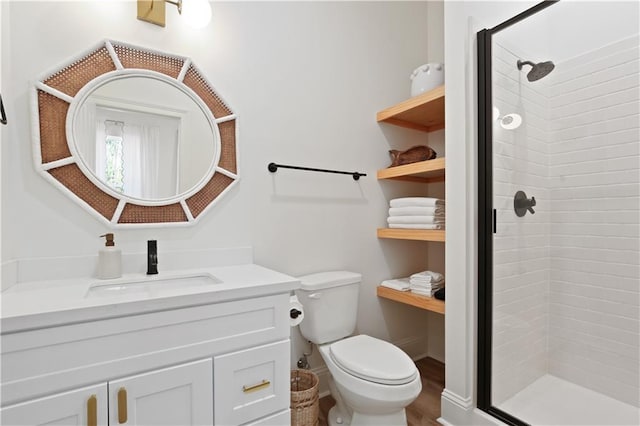 bathroom featuring hardwood / wood-style floors, vanity, toilet, and a tile shower