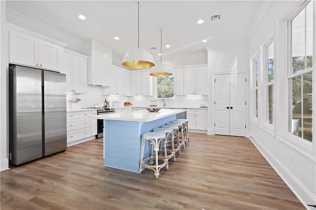 kitchen featuring white cabinets, light hardwood / wood-style flooring, tasteful backsplash, and stainless steel appliances