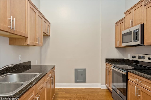 kitchen with dark stone countertops, wood-type flooring, appliances with stainless steel finishes, and sink