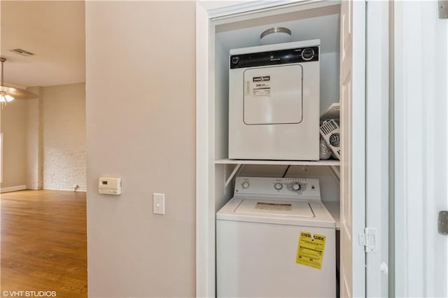 laundry area with stacked washer / drying machine and wood-type flooring