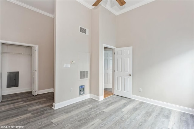 unfurnished bedroom with crown molding, a high ceiling, ceiling fan, and hardwood / wood-style flooring