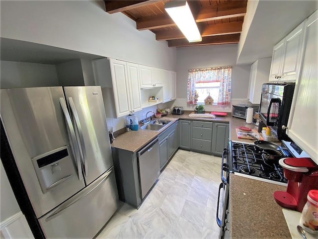 kitchen with beamed ceiling, appliances with stainless steel finishes, sink, light tile flooring, and wooden ceiling