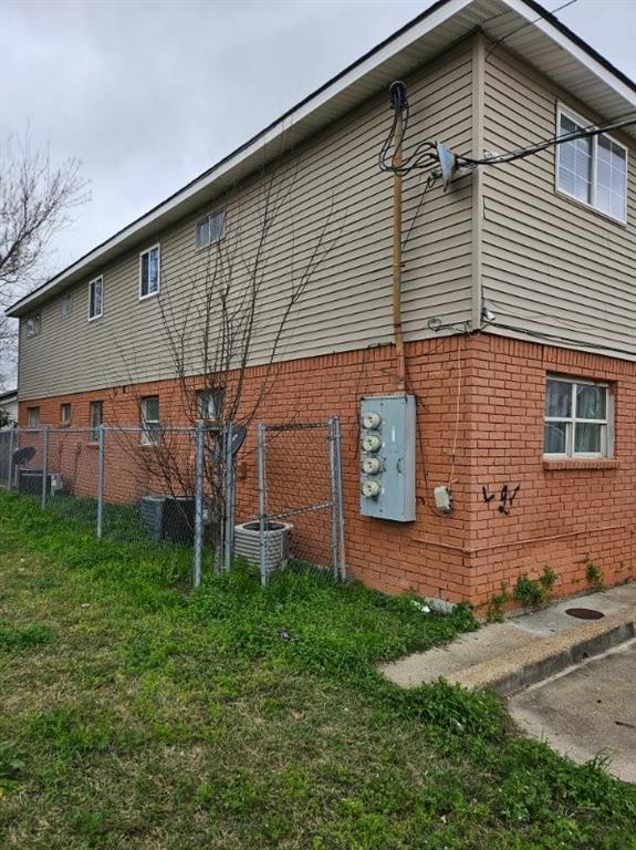 view of side of property with central AC unit and a lawn