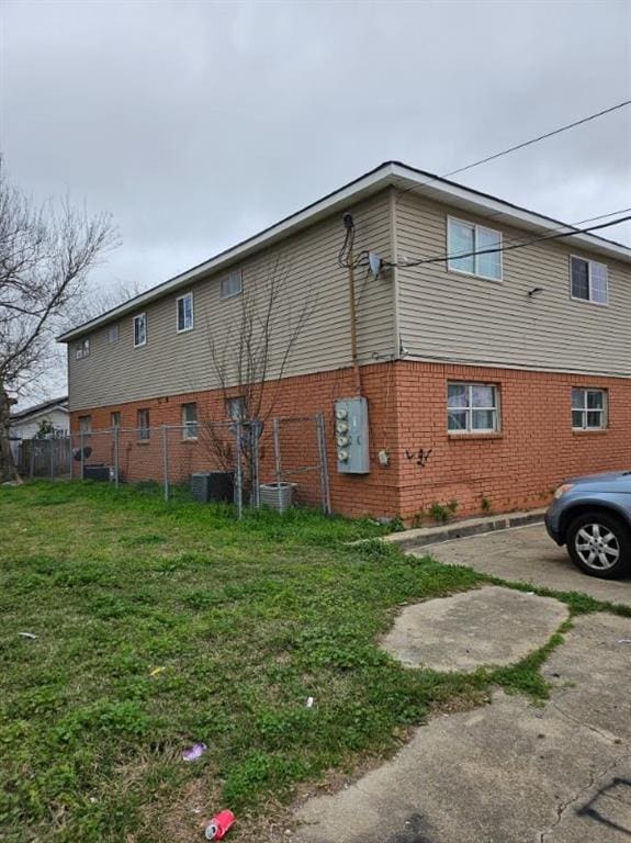 back of house featuring central AC unit and a lawn