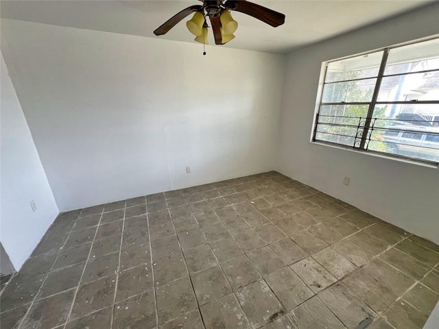 spare room with ceiling fan and dark tile flooring