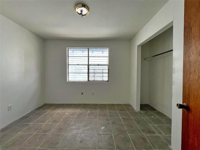 unfurnished bedroom featuring dark tile flooring and a closet