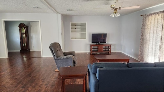 living room featuring a textured ceiling, dark wood-type flooring, built in shelves, and ceiling fan