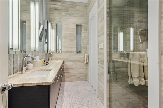 bathroom with a shower with door, tile flooring, tile walls, and dual vanity