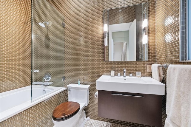 full bathroom featuring vanity, tile walls, combined bath / shower with glass door, tasteful backsplash, and toilet