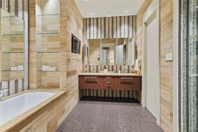 bathroom with tile walls, a relaxing tiled bath, and dual vanity