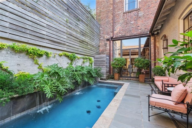 view of swimming pool with pool water feature, french doors, and a patio