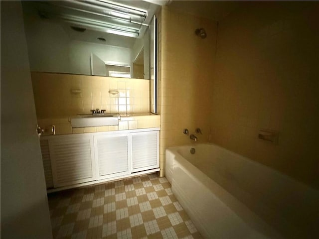 bathroom featuring tiled shower / bath combo, tile walls, backsplash, tile floors, and sink