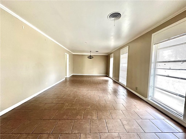 spare room with dark tile flooring, crown molding, and a healthy amount of sunlight