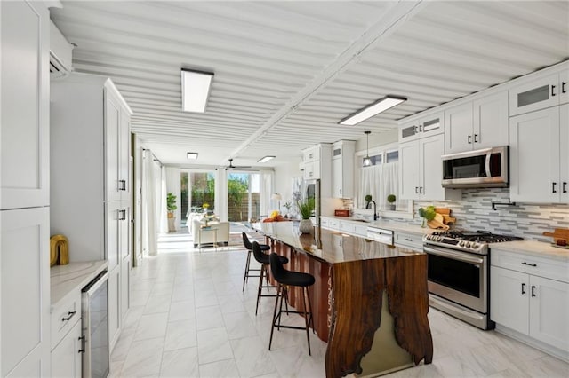 kitchen with white cabinetry, appliances with stainless steel finishes, a center island, and light stone countertops