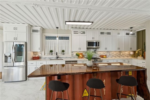 kitchen with a breakfast bar area, white cabinetry, hanging light fixtures, and appliances with stainless steel finishes