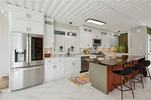 kitchen featuring white cabinetry, appliances with stainless steel finishes, dark stone countertops, a center island, and pendant lighting