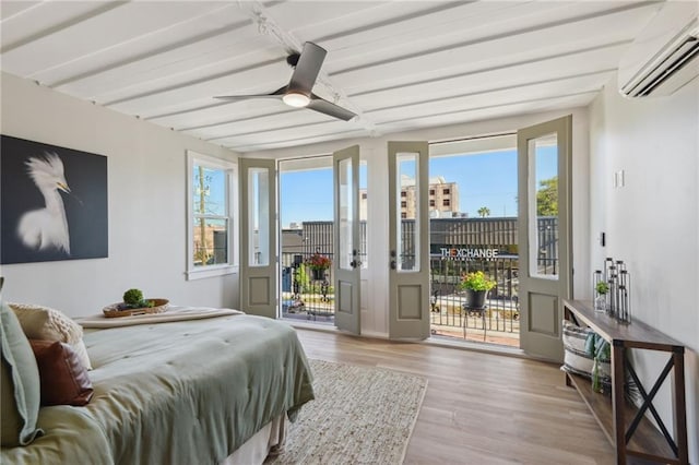 bedroom featuring a wall mounted air conditioner, light hardwood / wood-style floors, and multiple windows