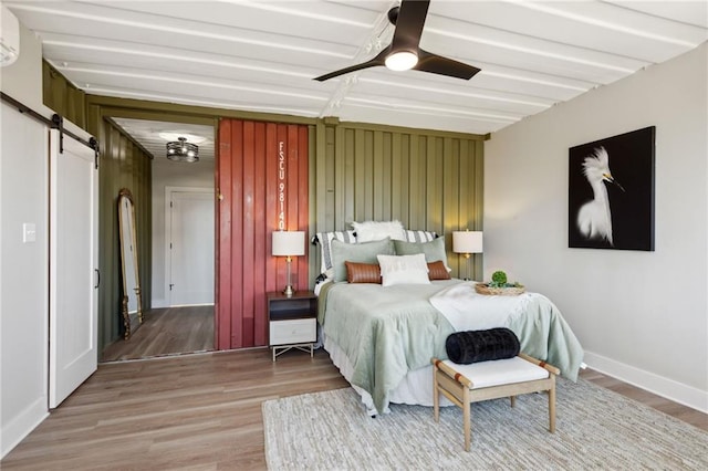 bedroom featuring a barn door, ceiling fan, and hardwood / wood-style flooring