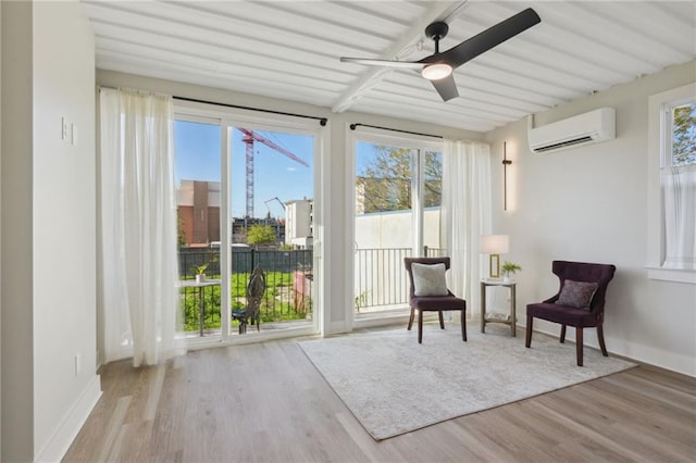 sitting room featuring a wall unit AC, ceiling fan, a healthy amount of sunlight, and light hardwood / wood-style flooring