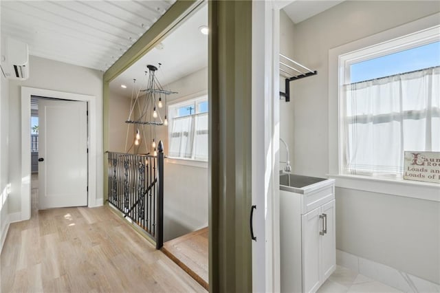 corridor with sink, a wealth of natural light, light wood-type flooring, and a wall mounted air conditioner