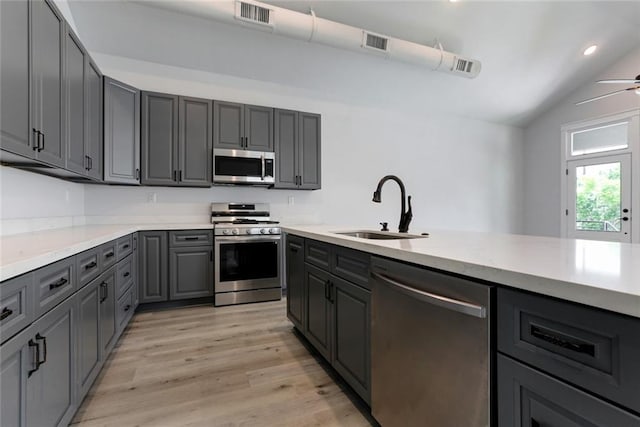 kitchen with ceiling fan, sink, light hardwood / wood-style flooring, stainless steel appliances, and vaulted ceiling