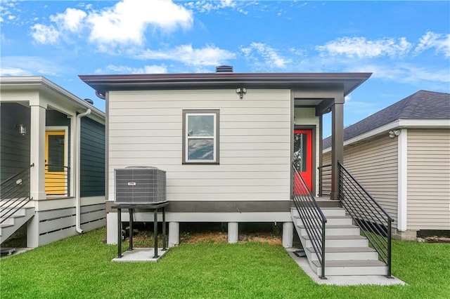 back of house featuring central air condition unit and a yard