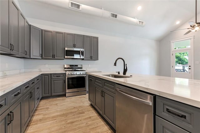 kitchen featuring appliances with stainless steel finishes, ceiling fan, sink, light wood-type flooring, and lofted ceiling