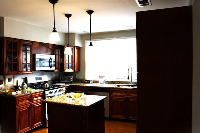 kitchen featuring stainless steel appliances, a kitchen island, dark hardwood / wood-style flooring, pendant lighting, and light stone countertops