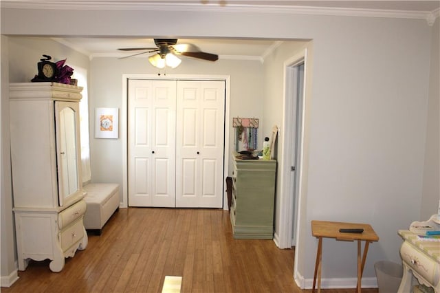 interior space featuring light wood-type flooring, ceiling fan, crown molding, and a closet