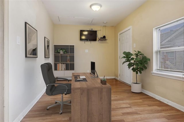 home office with light wood-style flooring and baseboards