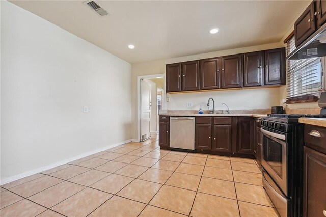 kitchen with sink, appliances with stainless steel finishes, light tile patterned floors, and dark brown cabinetry