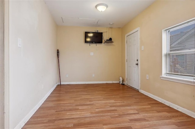 spare room featuring baseboards and light wood finished floors