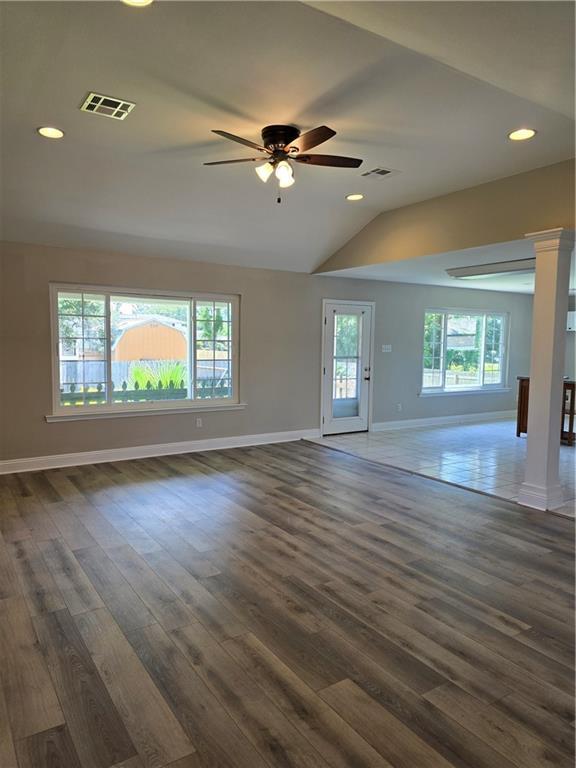 unfurnished living room featuring ceiling fan, dark wood-type flooring, a healthy amount of sunlight, and vaulted ceiling