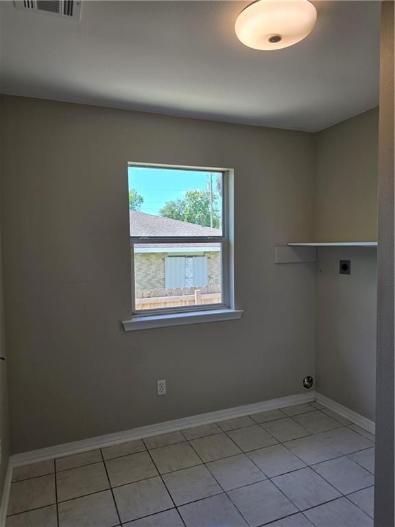 laundry area with electric dryer hookup and light tile patterned floors