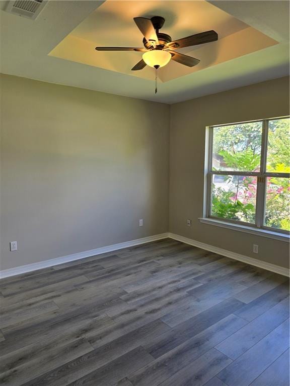 spare room featuring dark hardwood / wood-style floors, a raised ceiling, and ceiling fan