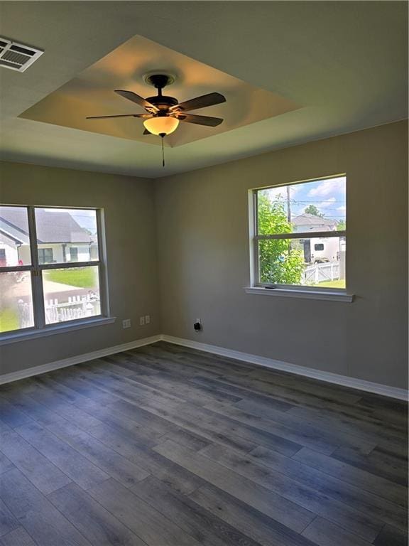 unfurnished room with dark hardwood / wood-style floors, a raised ceiling, and ceiling fan