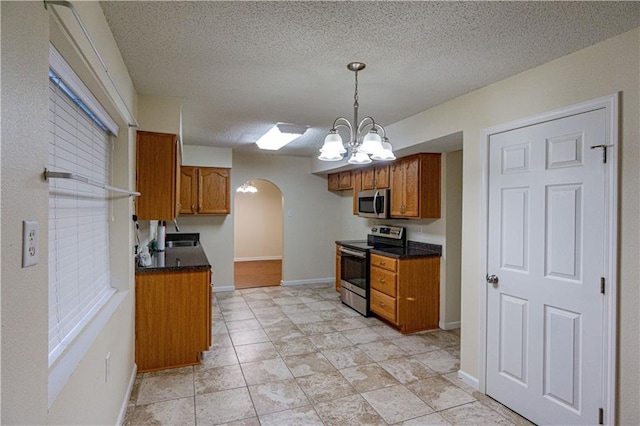 kitchen featuring appliances with stainless steel finishes, light tile floors, a textured ceiling, hanging light fixtures, and a chandelier