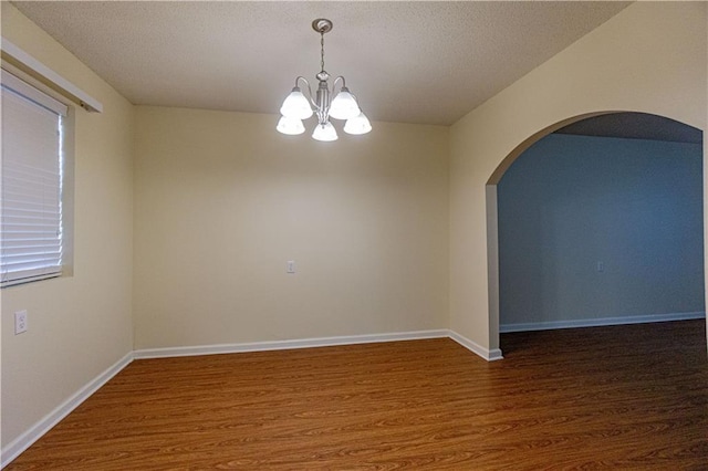 empty room featuring an inviting chandelier and dark wood-type flooring