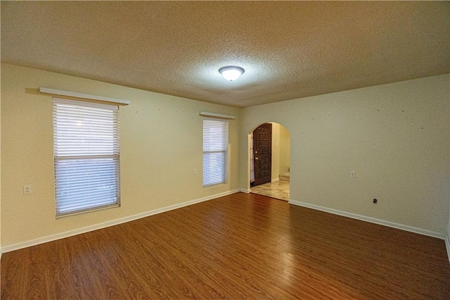 unfurnished room with plenty of natural light, hardwood / wood-style floors, and a textured ceiling