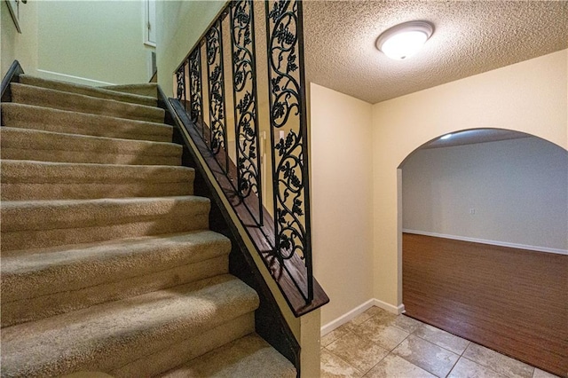 stairs featuring tile flooring and a textured ceiling