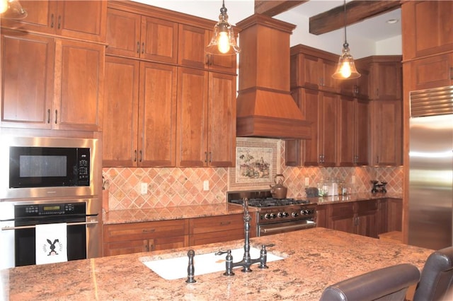 kitchen with pendant lighting, built in appliances, a kitchen bar, and custom exhaust hood