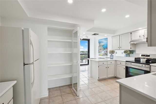 kitchen featuring visible vents, stainless steel electric range oven, freestanding refrigerator, a peninsula, and under cabinet range hood