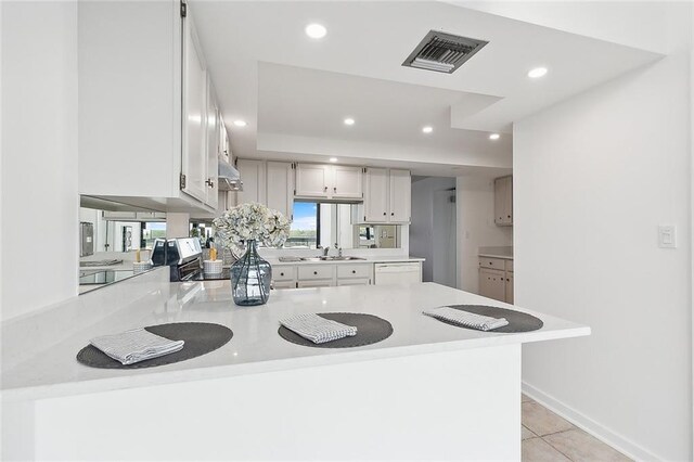 kitchen featuring kitchen peninsula, white cabinetry, sink, and light tile patterned flooring