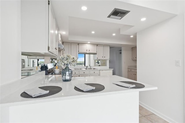 kitchen with light tile patterned flooring, recessed lighting, a peninsula, visible vents, and light countertops