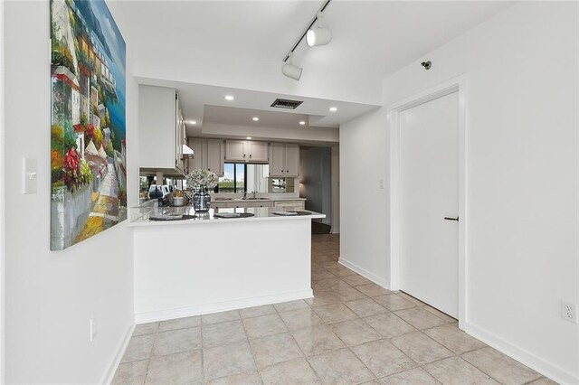 kitchen with kitchen peninsula, track lighting, gray cabinetry, sink, and light tile patterned floors