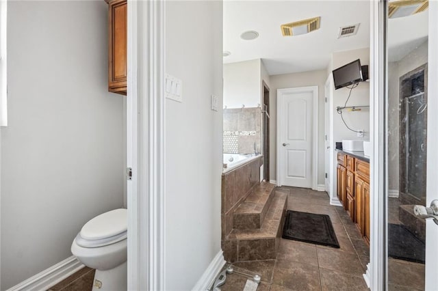 bathroom featuring tiled bath, vanity, toilet, and tile flooring