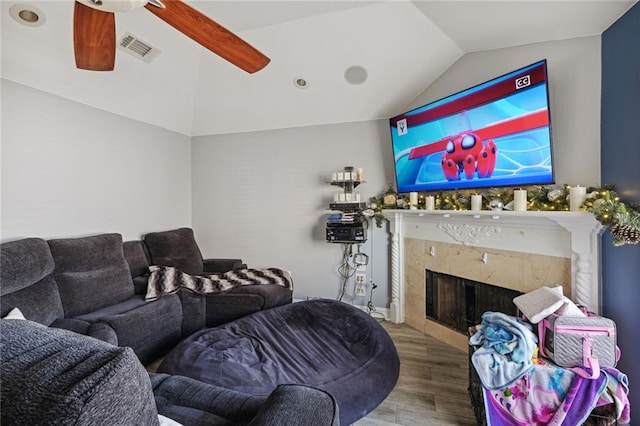 living room featuring hardwood / wood-style floors, vaulted ceiling, ceiling fan, and a fireplace