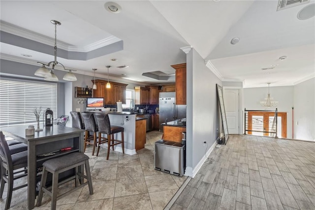 interior space with a chandelier, crown molding, hanging light fixtures, and a tray ceiling