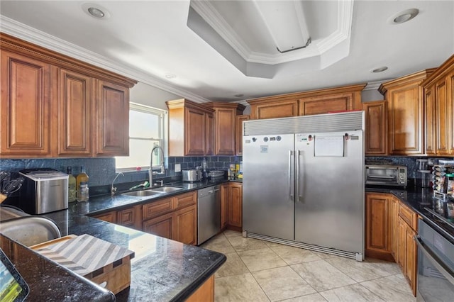 kitchen with crown molding, backsplash, appliances with stainless steel finishes, a raised ceiling, and sink